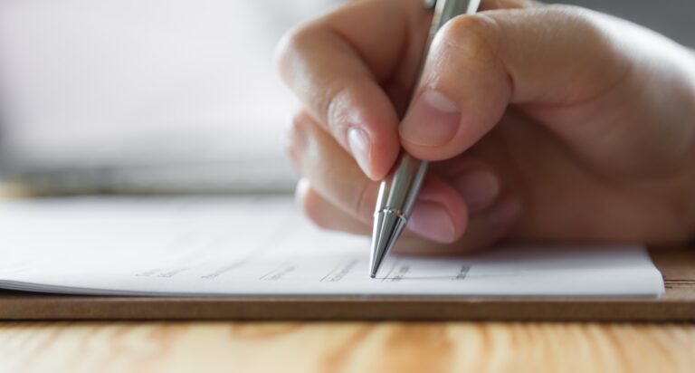 Hand with pen over application form