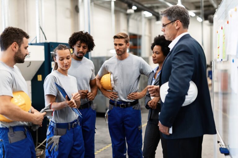 Female worker showing production reports to company managers in a factory.