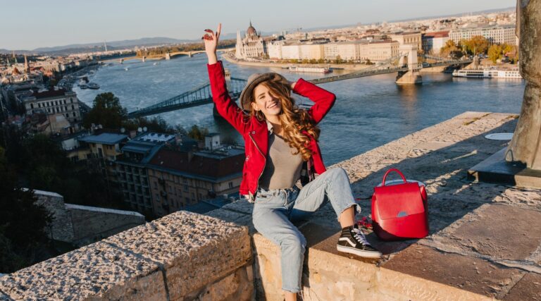 linda-garota-com-um-casaco-vermelho-da-moda-posando-em-um-telhado-no-fundo-da-cidade